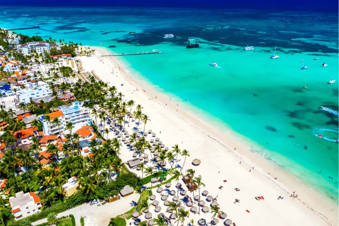 Rajskie plaże, palmy i turkusowe morze – idealne miejsce, kiedy na rejs po Karaibach. Widać hotele i łodzie.