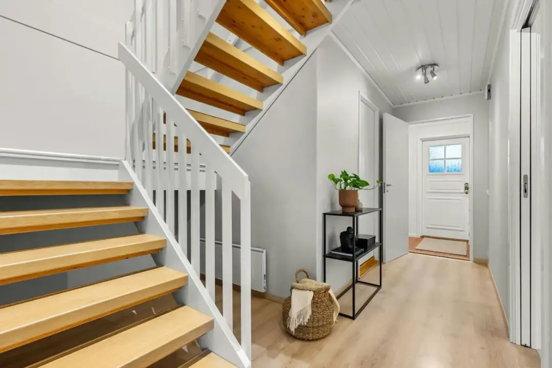Nowoczesne schody z drewna i białej balustrady. Inspiracja, jak zaprojektować schody, by były funkcjonalne i estetyczne.