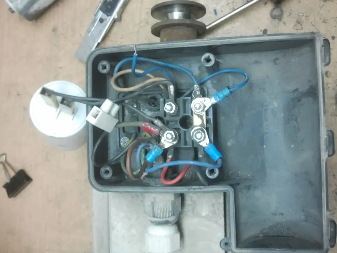 Schemat połączeń silnika elektrycznego z kondensatorem rozruchowym. Widać przewody, zaciski i kondensator.