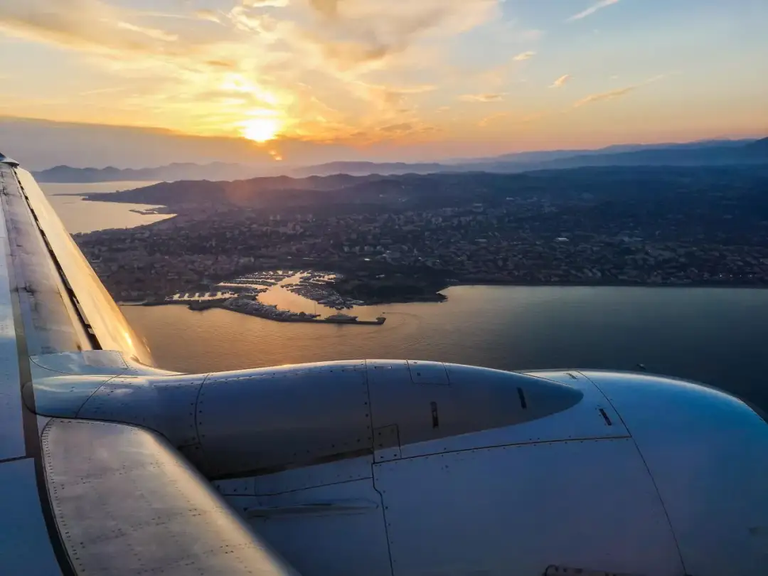 Widok z samolotu na wybrzeże Włoch o zachodzie słońca. Czy loty do Włoch są bezpieczne? Tak, ten widok potwierdza, że podróż jest warta zachodu.