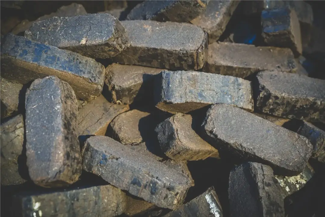 Stos brykietu drzewnego, ciemne, prostokątne kawałki paliwa.