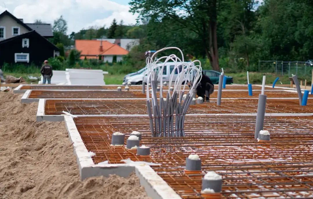 Przygotowanie terenu pod budowę: jak położyć fundament. Widoczne zbrojenie, rury i izolacja.