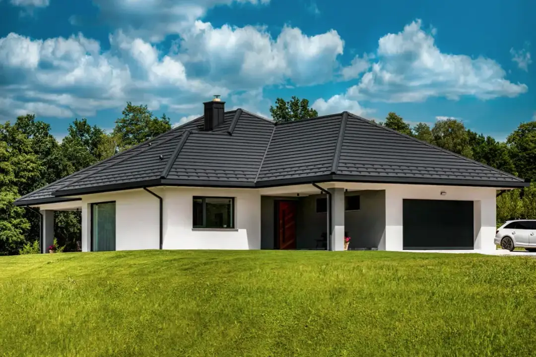 Nowoczesny dom z ciemnym dachem i garażem, otoczony zielenią. Zastanawiasz się, ile waży dom?