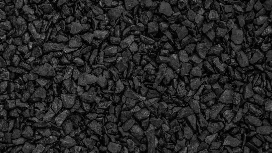 Zbliżenie na czarny ekogroszek, widoczne drobne, nieregularne bryłki węgla.