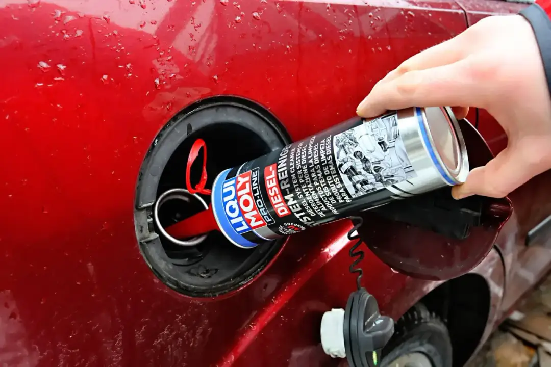 Ręka wlewa do baku czerwonego samochodu środki do czyszczenia wtryskiwaczy Liqui Moly Diesel.