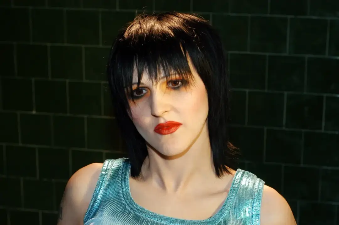 Agnieszka Chylińska z charakterystyczną fryzurą i makijażem, w błyszczącej, błękitnej bluzce.