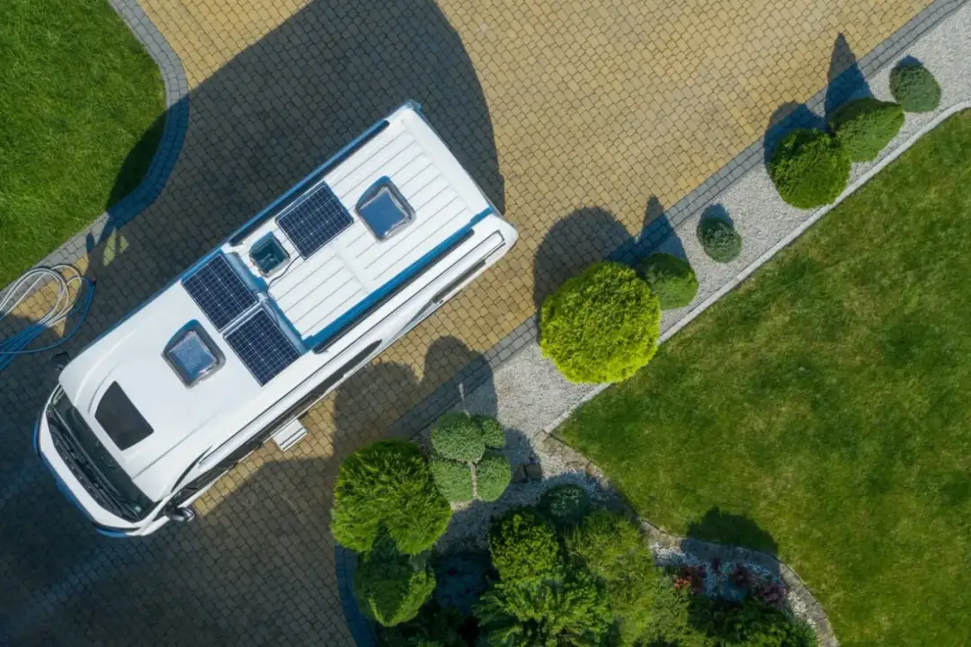 Biała przyczepa kempingowa z panelami słonecznymi na dachu, idealna do nauki, jak uszczelnić dach przyczepy kempingowej.