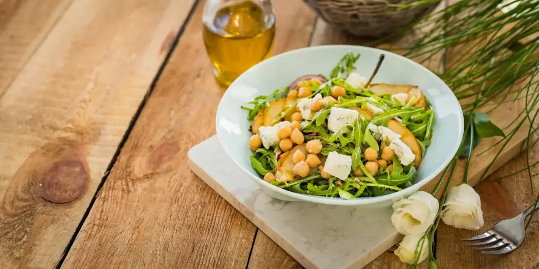 Sałatka z rukolą, gruszką, ciecierzycą i serem pleśniowym. Aby rukola nie była gorzka, warto dodać słodkie składniki.