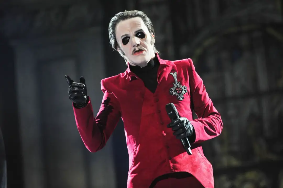 Kto to jest mim? To wokalista Ghost w czerwonym fraku, z makijażem i mikrofonem.