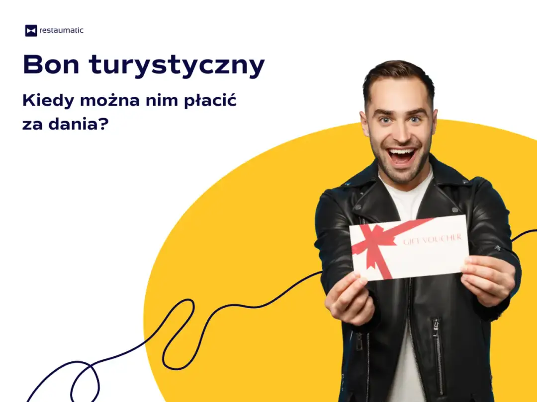Uśmiechnięty mężczyzna trzyma bon podarunkowy. Czy bon turystyczny można wykorzystać w restauracji na pyszne dania?