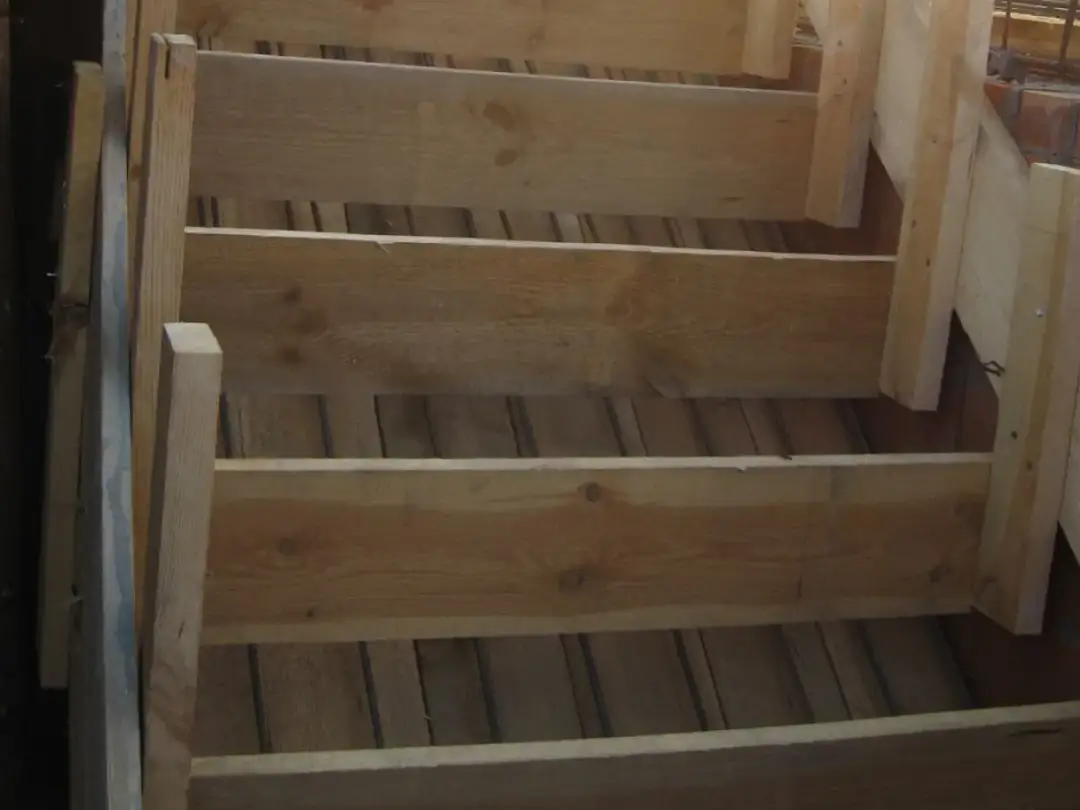 Drewniany szalunek schodów, gotowy do wylania betonu. Pokazuje, jak zrobić szalunek na schody półokrągłe.