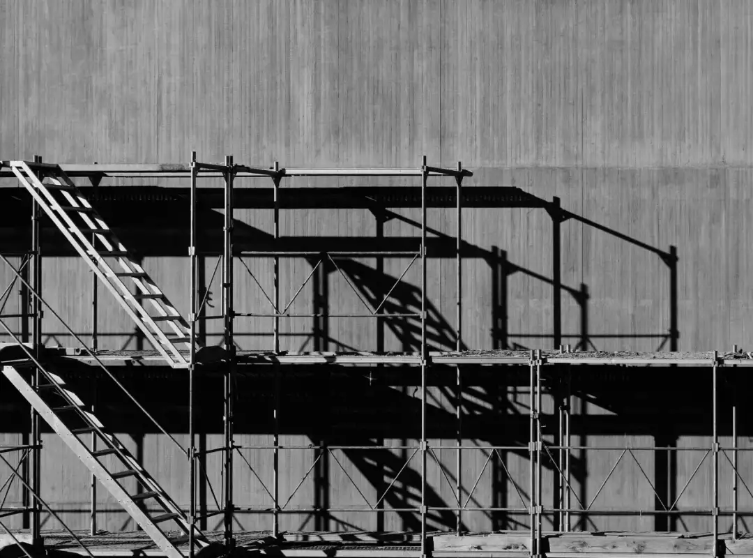 Rusztowanie z drabiną na tle betonowej ściany. Pokazuje, jak ustawić rusztowanie na schodach, tworząc bezpieczne przejście.