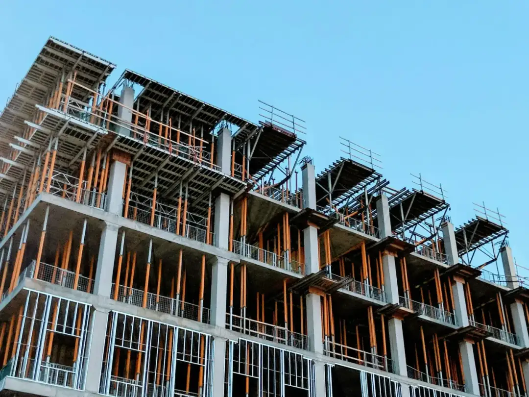 Budowa wielopiętrowego budynku z betonowymi słupami i drewnianymi podporami.