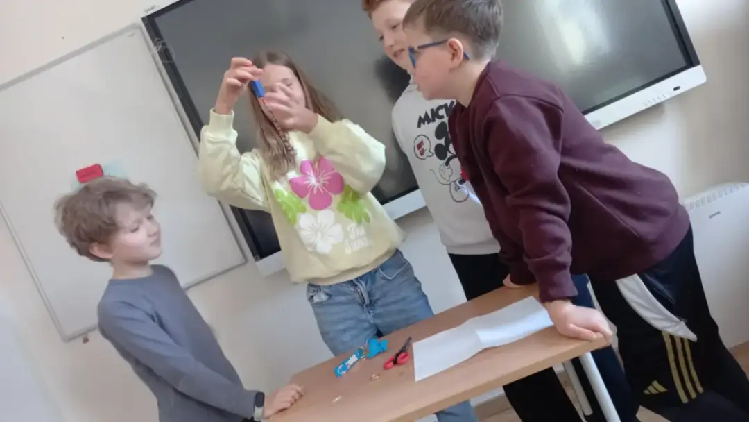 Dzieci przeprowadzają eksperyment z magnesem, trzymając go nad łańcuszkiem.