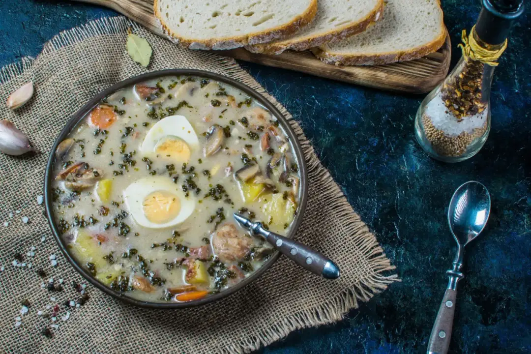 Aksamitny żurek z jajkiem i kiełbasą, idealny do doprawienia czosnkiem, majerankiem i pieprzem. Podany z chlebem.
