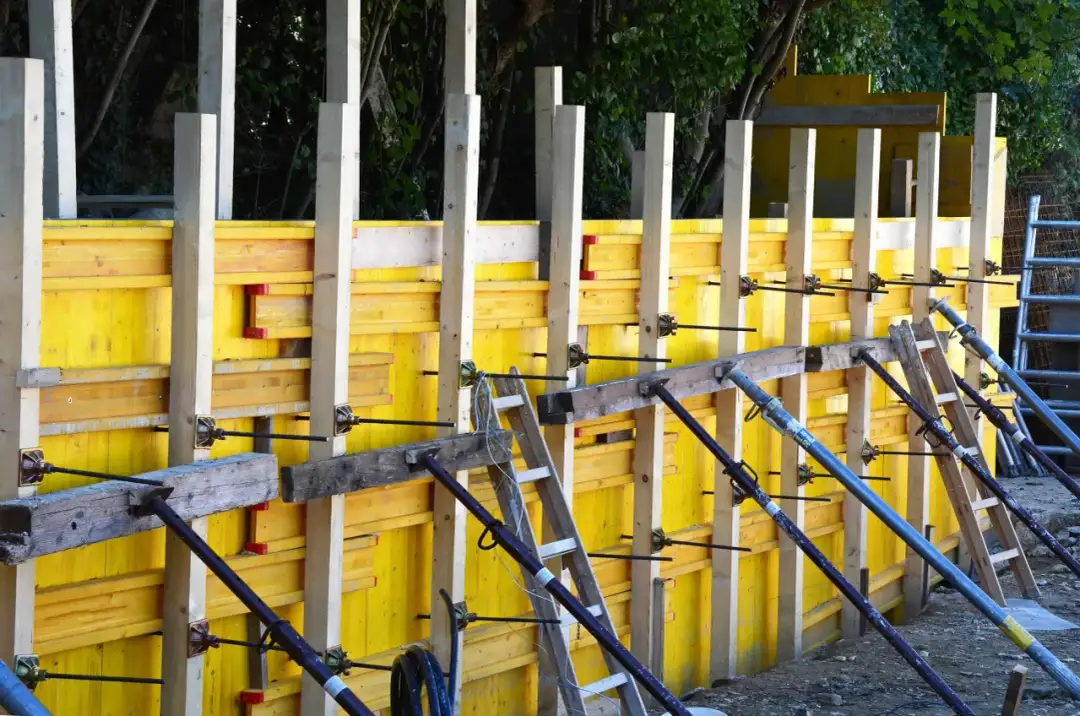 Szalunek co to? Żółte płyty i drewniane słupy tworzą konstrukcję do wylewania betonu.