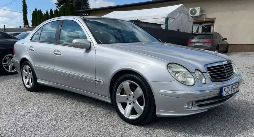 Srebrny Mercedes E500 W211 na żwirowym podjeździe, gotowy na podróż.