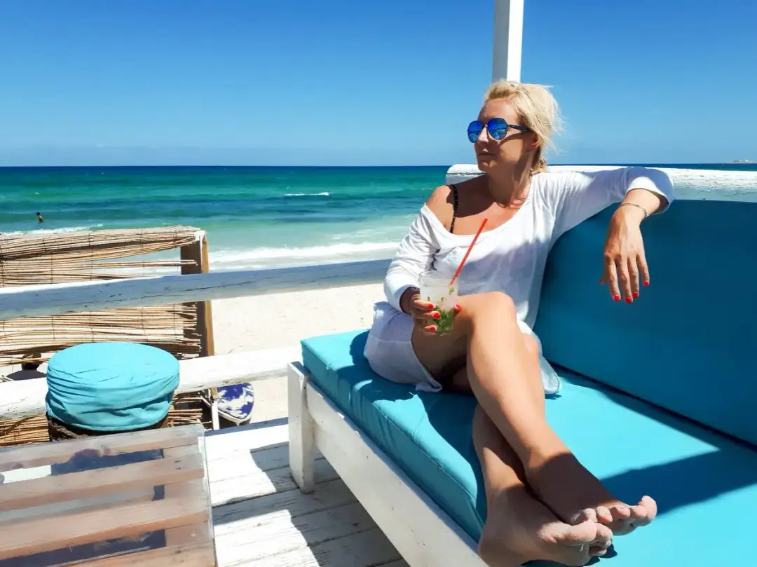 Kobieta z drinkiem na plaży w Tunezji. Czy Tunezja jest bezpieczna dla kobiet? Tak, można tu odpoczywać.