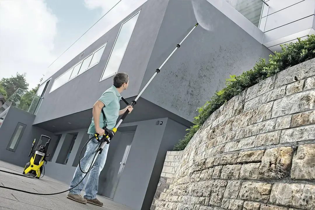 Mężczyzna myje elewację domu myjką Karcher z teleskopową lancą. Idealny wybór, jaki Karcher do mycia elewacji.