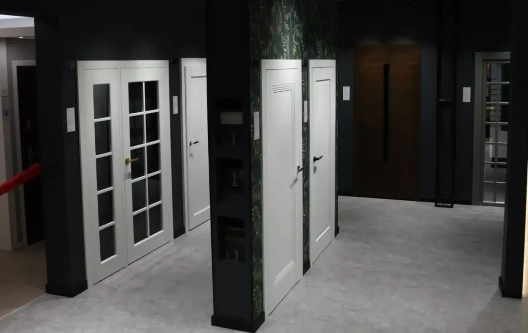 Salon drzwi w Łodzi: białe drzwi dwuskrzydłowe z przeszkleniem, białe drzwi jednolite, brązowe drzwi wejściowe.