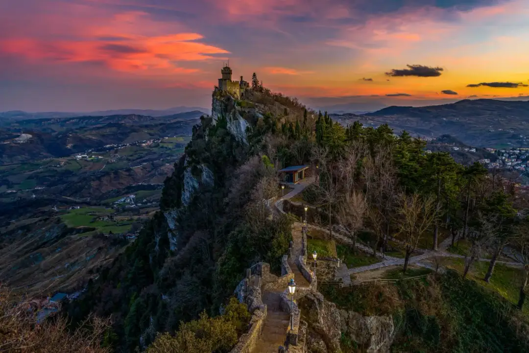 Zachód słońca nad San Marino, krajem, który może być najstarszy. Wieże na skalistym szczycie górują nad doliną.