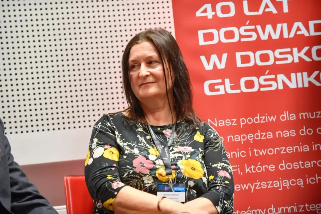 Maria Gutowska, córka Niemena, w kwiecistej sukience, z uśmiechem na twarzy, na tle napisu "40 lat doświadczenia w doskonałym brzmieniu".
