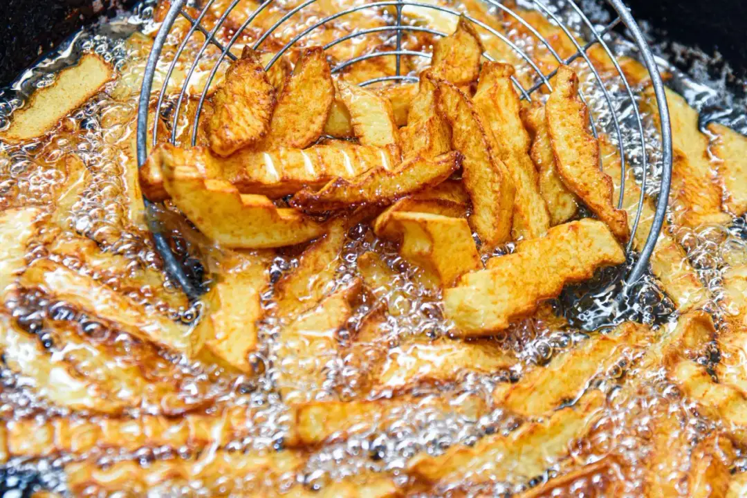 Złociste frytki smażą się w gorącym oleju. Zastanawiasz się, ile razy można smażyć frytki na tym samym oleju, by były idealne?