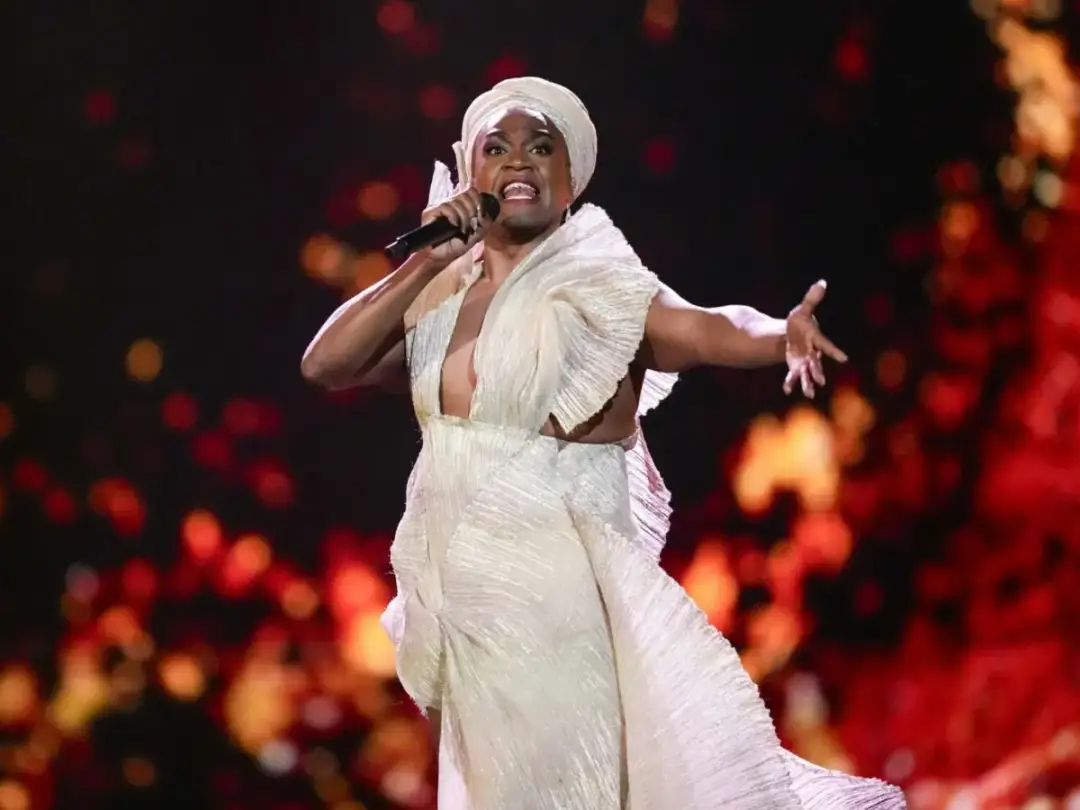 Artystka w białej kreacji śpiewa na scenie. Czy Australia jest w Europie? Nie, to odległy kontynent.