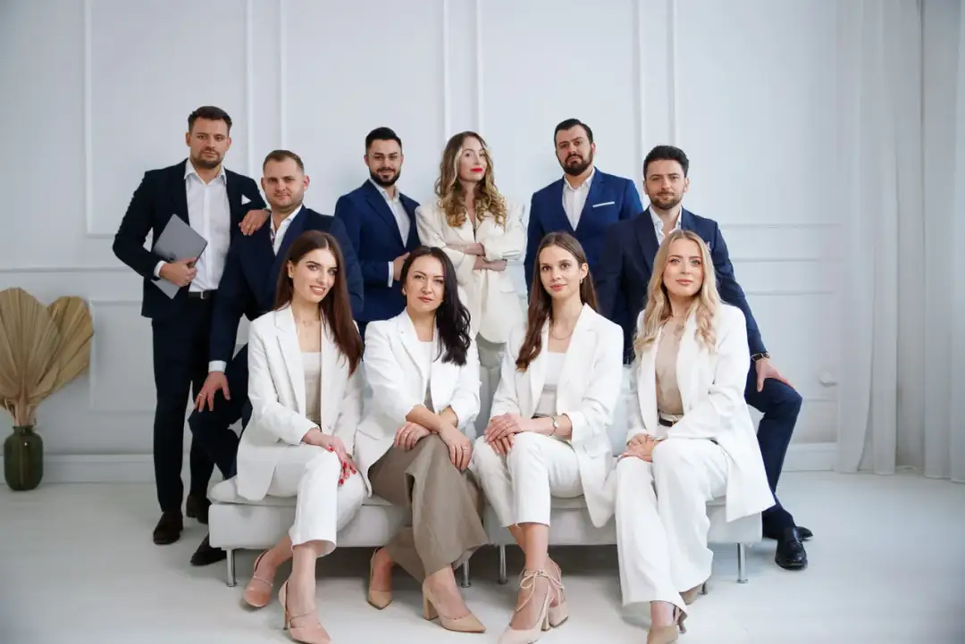 Grupa profesjonalistów w garniturach, w tym kobiety i mężczyźni, pozuje do zdjęcia.