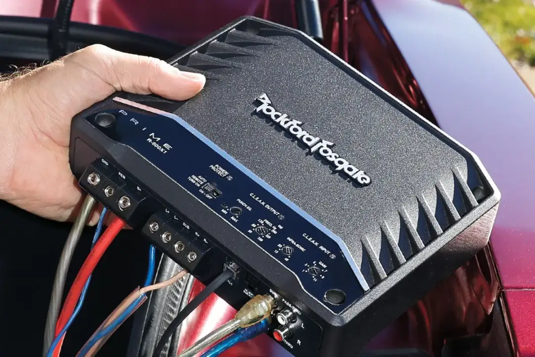 Podłączanie wzmacniacza samochodowego Rockford Fosgate. Czerwony kabel to plus, a czarny to minus dla głośników.