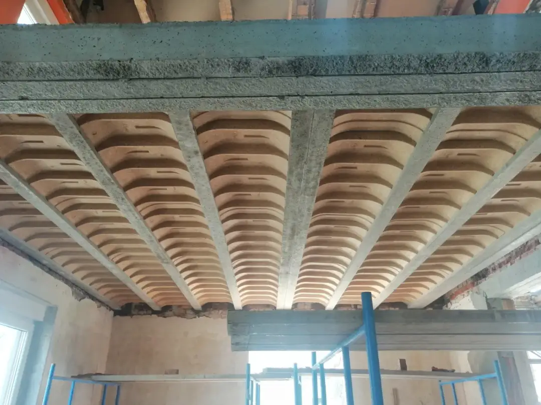 Widok od dołu na betonowy strop belkowo-pustakowy, gdzie widać żebra i pustaki ceramiczne. To właśnie co to strop.