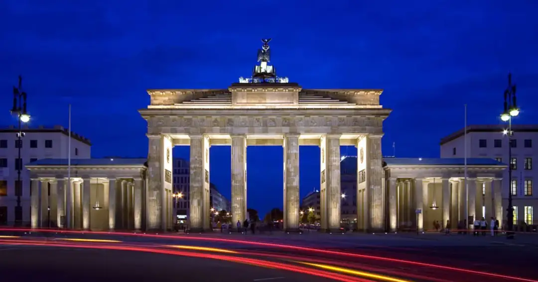 Brama Brandenburska nocą, z rozmazanymi światłami samochodów. Ciekawe ciekawostki o Berlinie czekają!