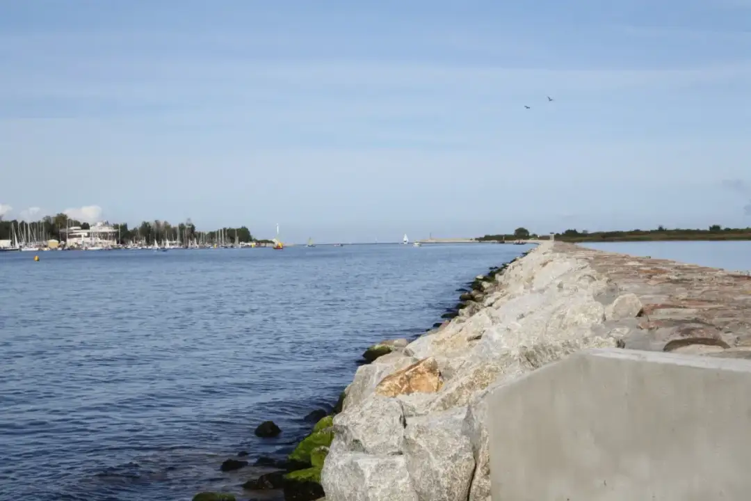 Kamienny falochron w Gdańsku, gdzie widać liczne żaglówki i statki. Czy Wisła płynie przez Gdańsk? Tak, jej ujście jest blisko.