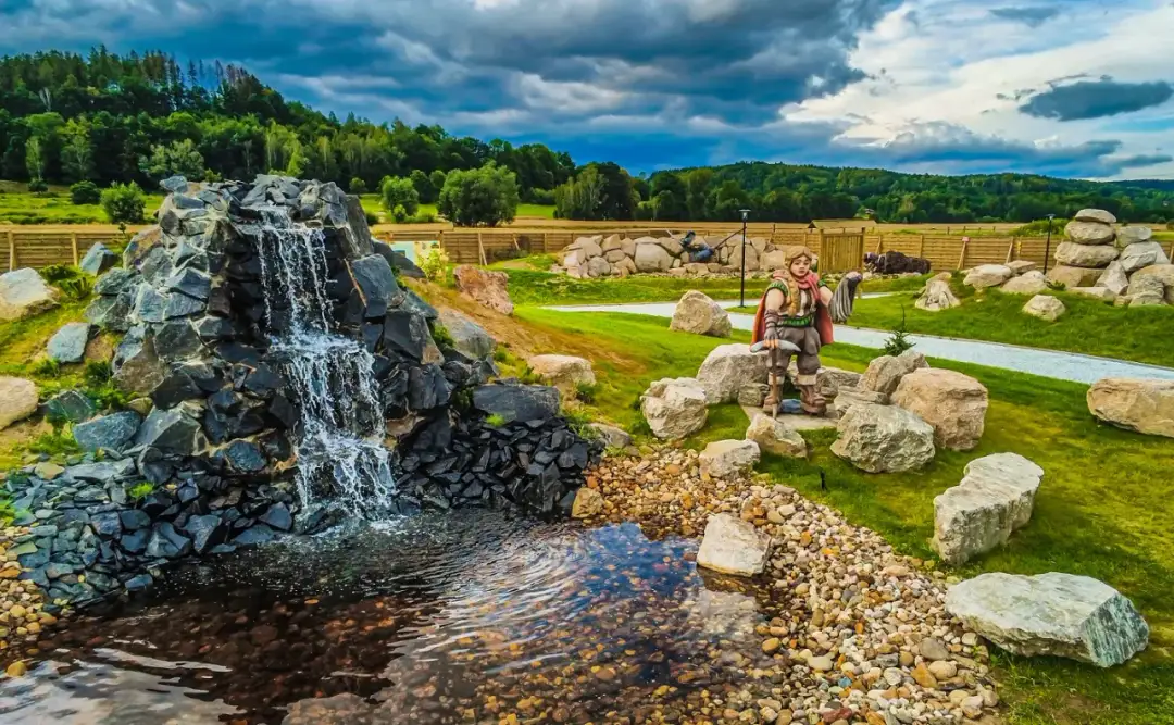 Kamienny wodospad i rzeźba krasnoludka w zielonym parku krajobrazowym.