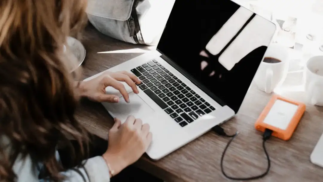 Kobieta pracuje na laptopie, szukając sposobów, jak bezpiecznie ukryć przed obecnym szefem szukanie nowej pracy.