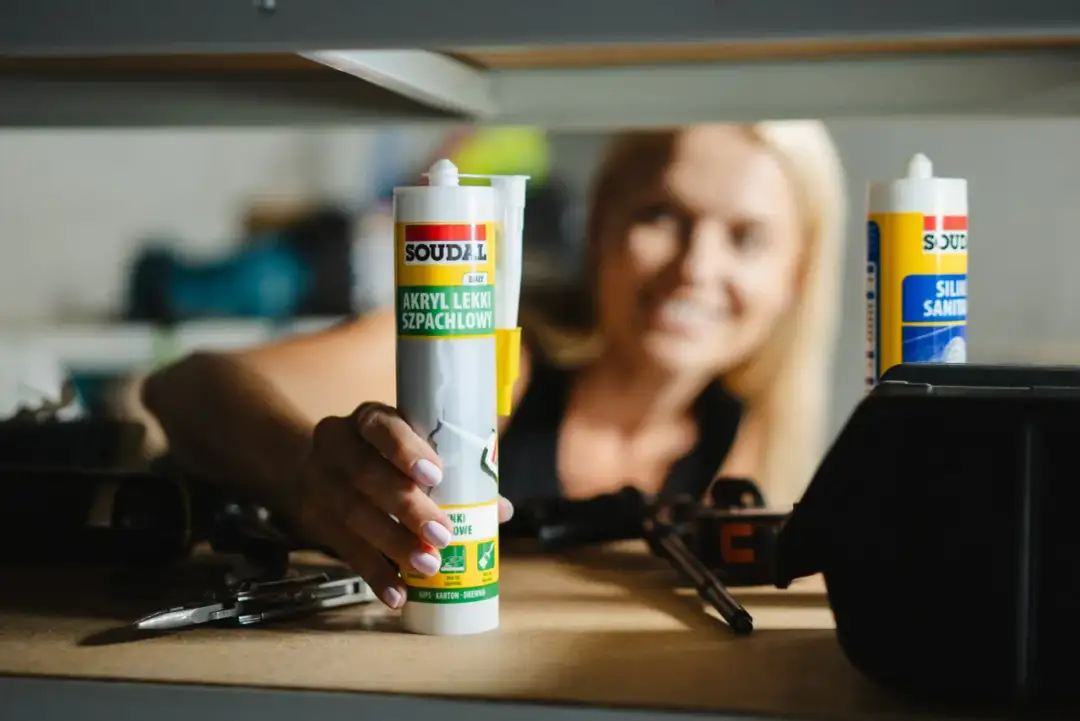 Kobieta trzyma tubkę akrylu. Zastanawia się, ile schnie akryl, by móc dokończyć remont.