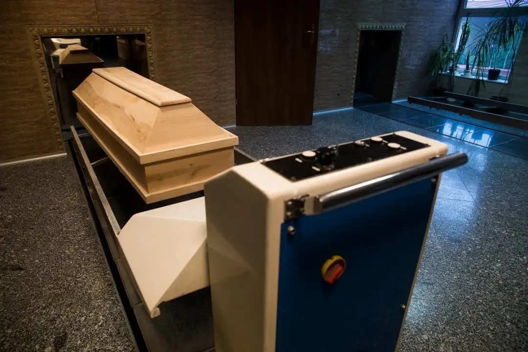 Drewniana trumna na taśmie transportowej przed krematorium.