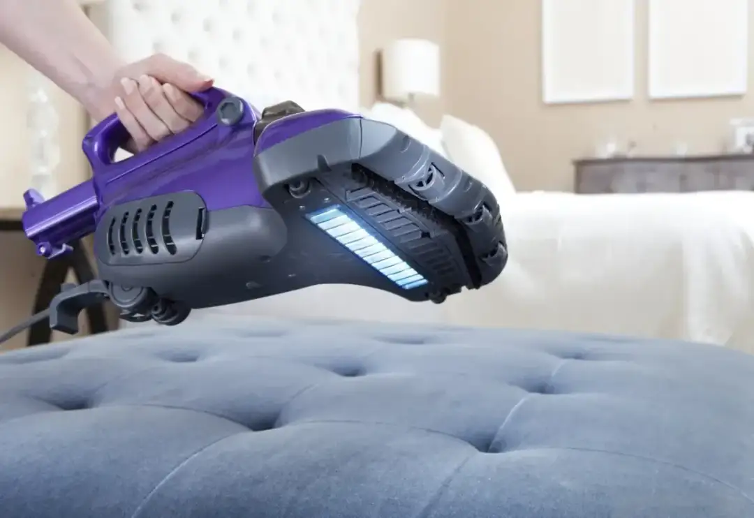Fioletowy odkurzacz z filtrem HEPA czyści materac, odpowiadając na pytanie, czy odkurzacze z filtrem HEPA naprawdę usuwają roztocza z materaca.