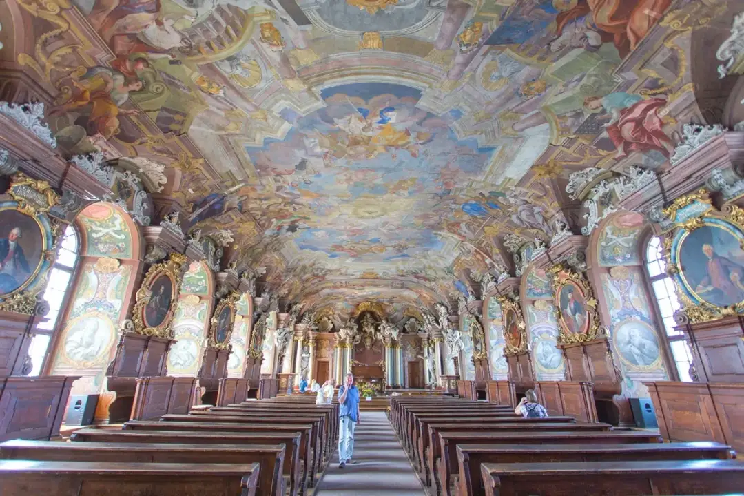 Wrocławskie muzea zachwycają. Wnętrze z barokowym freskiem na suficie, portretami i drewnianymi ławami.