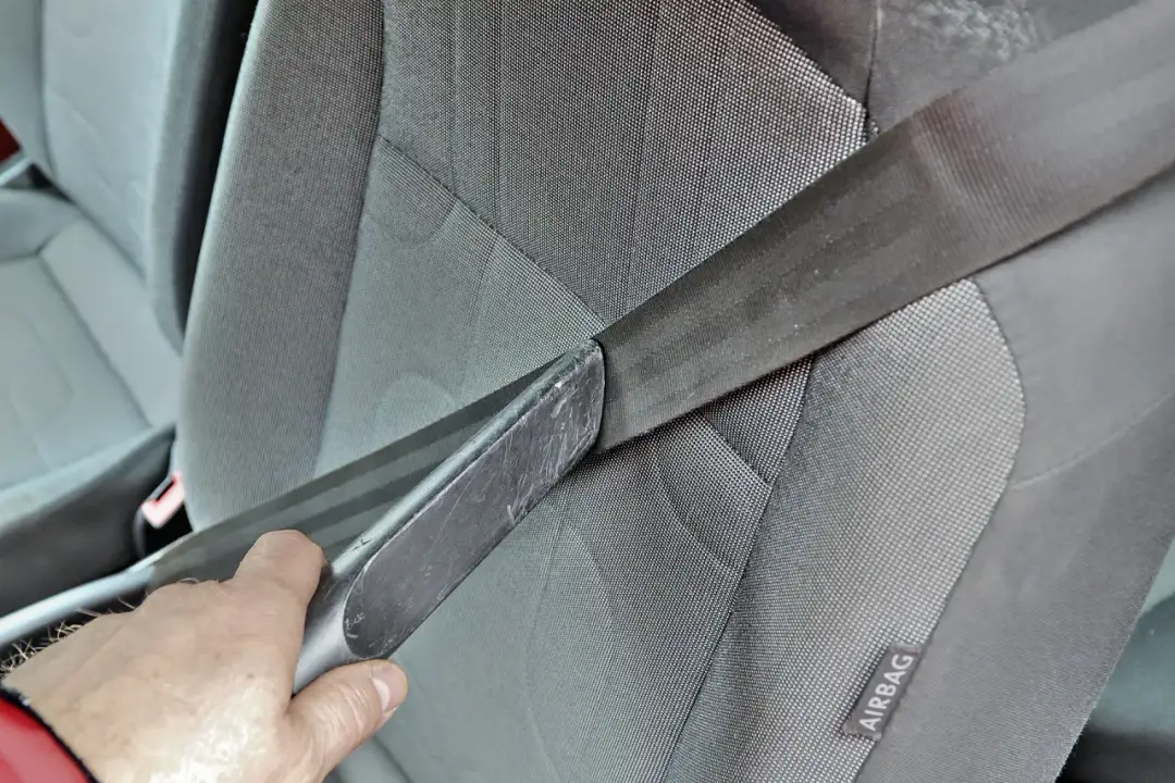 Dłoń trzyma narzędzie, które może pomóc w naprawie zwijacza pasów bezpieczeństwa w samochodzie.