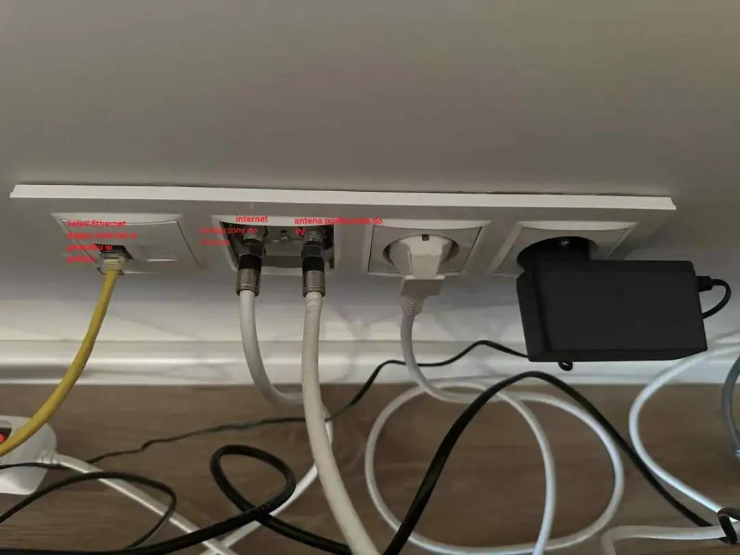 Gniazda ścienne z podłączonym kablem Ethernet, antenowym i zasilającym.