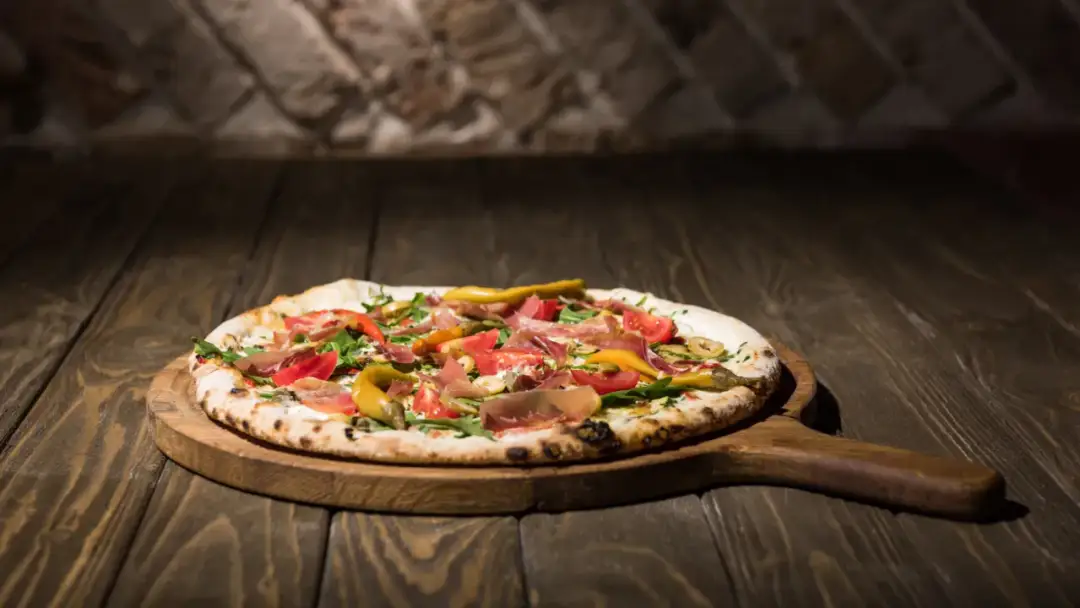 Pyszna pizza na drewnianej desce, idealna do pieczenia na kamieniu. Zobacz, jaki kamień do pizzy wybrać, by uzyskać chrupiący spód!