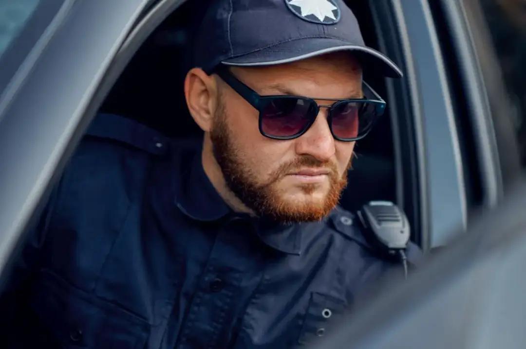 Policjant w okularach przeciwsłonecznych i czapce, gotowy do akcji. Marzysz, jak zostać policjantem kryminalnym?