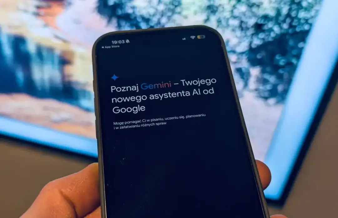 Dłoń trzyma smartfon z ekranem wyświetlającym komunikat o asystencie AI Gemini od Google.