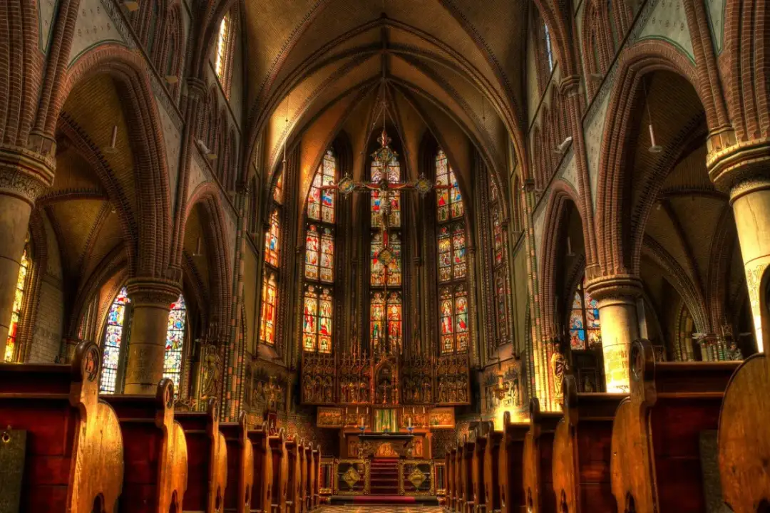 Wnętrze kościoła z witrażami i krucyfiksem. Krzyżmo, co to jest? To symbol wiary, widoczny w centrum.