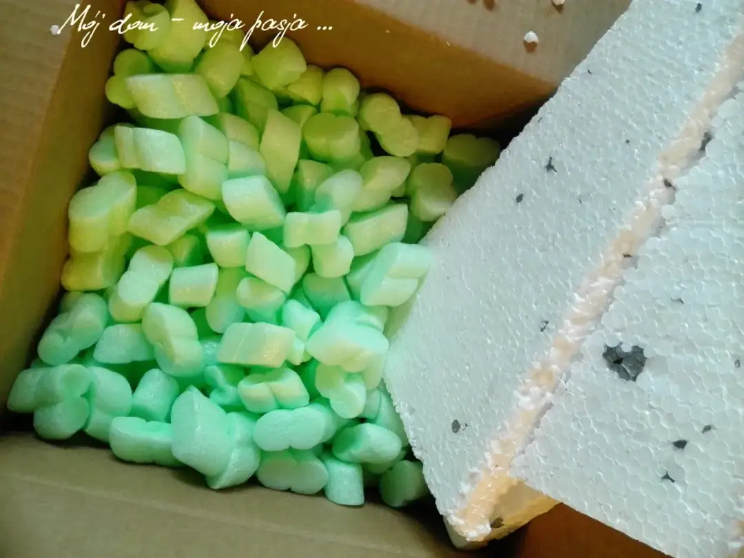 Zielone i białe resztki styropianu w kartonie.