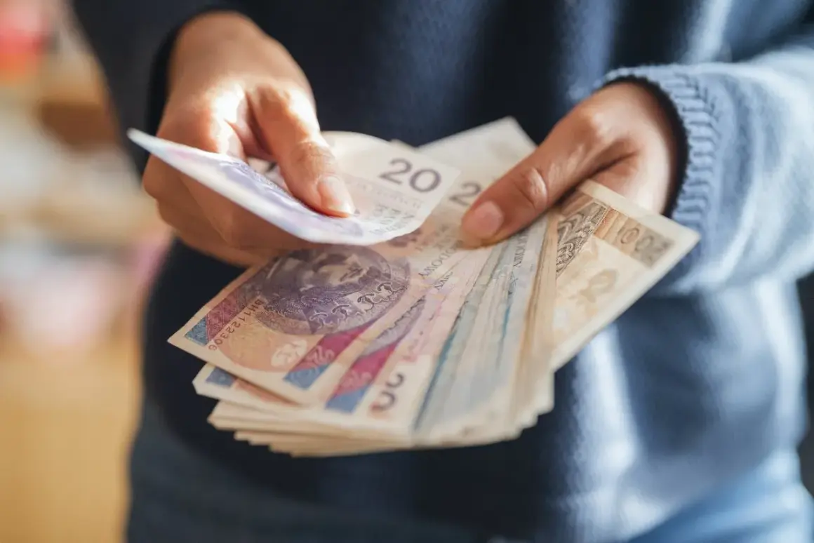 Ręce liczą polskie banknoty. Zastanawiasz się, ile wzrośnie emerytura z OFE po 65 roku życia?
