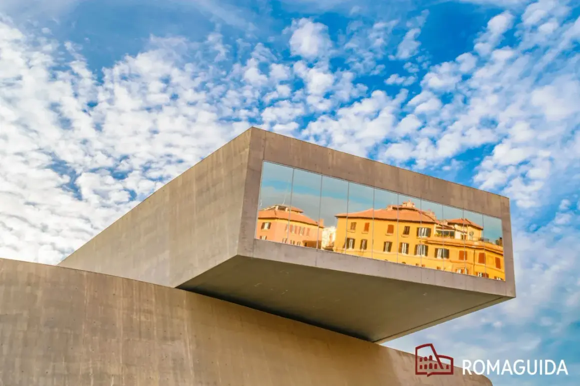 Il MAXXI - Museo Nazionale delle Arti del XXI Secolo riflette edifici storici romani sotto un cielo azzurro e nuvoloso.