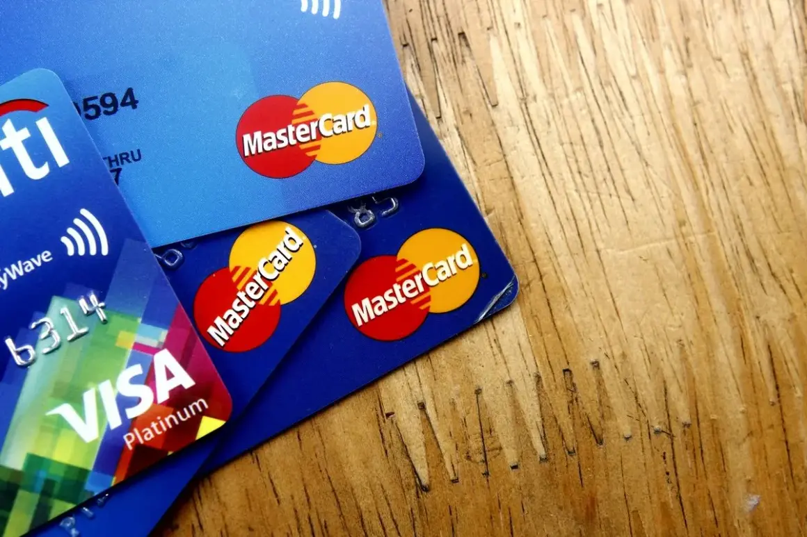 Kilka kart płatniczych, w tym Visa Platinum i karty debetowe z logo MasterCard, leżą na drewnianym blacie.