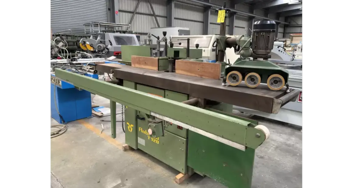 Une toupie tenonneuse verte, machine à bois industrielle, prête pour des travaux de menuiserie précis.